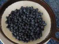 Heidelbeeren sortieren und in einem Sieb unter...